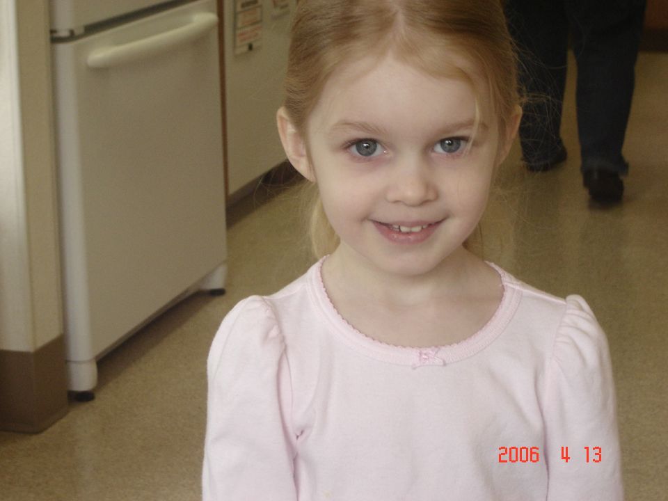 Young girl with blonde hair and blue eyes smiles at the camera