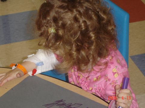 1993 Ford Bronco - A young child with curly hair is seated at a table, engaged in drawing with a purple marker.
