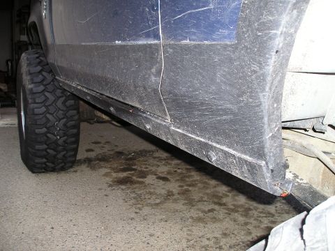 1986 Ford Bronco II - Close-up view of the lower side panel and wheel well of a blue vehicle.