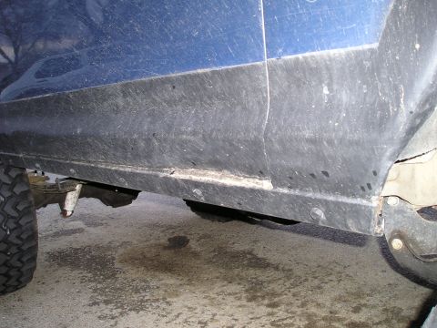 1986 Ford Bronco II - The lower body panel and wheel well of a blue vehicle are visible in this close-up shot.