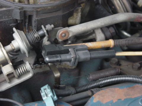 1982 Ford Crown Victoria LTD - Close-up view of the carburetor linkage mechanism, showing a black plastic connector and spring.