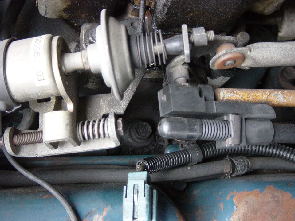 Close-up of carburetor linkage with springs and electrical connectors