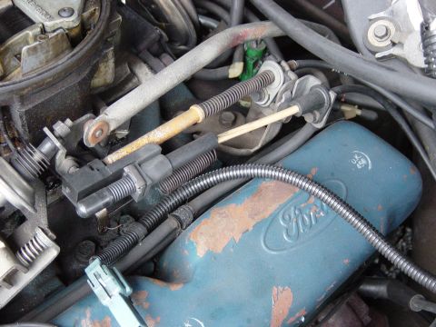 1982 Ford Crown Victoria LTD - This photo shows the carburetor linkage and a blue engine component with the Ford logo.