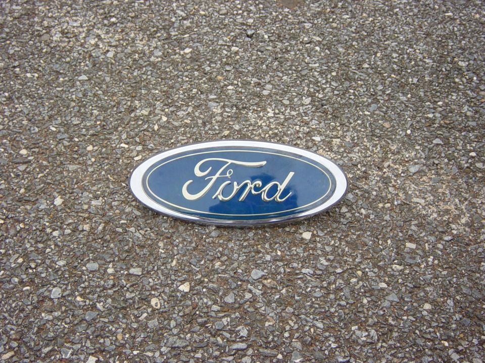 Blue Ford oval emblem with chrome trim on asphalt
