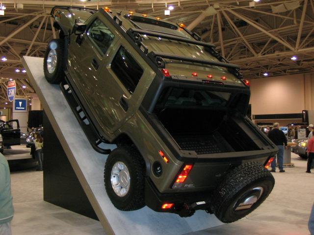 Hummer H2 SUT tilted on a ramp display at an indoor auto show