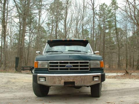 1988 Ford Bronco - Front view of a green Ford truck with a chrome bumper and grille, parked outdoors.