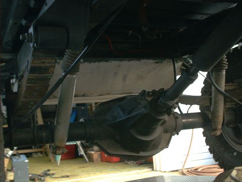 1978 Ford Bronco - The rear axle assembly, including the differential, driveshaft, and suspension components, is visible from below.