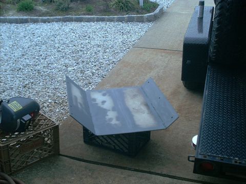 1978 Ford Bronco - A metal part is resting on milk crates outdoors, with a trailer visible to the right.