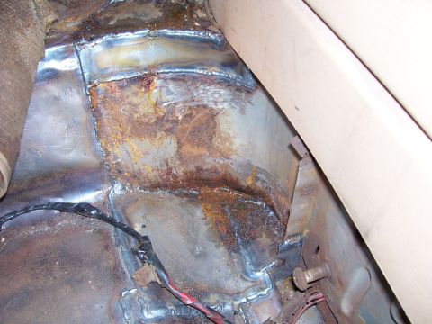 1984 Ford Bronco - The interior floor pan shows significant rust and repair work, with visible welding and electrical wiring.