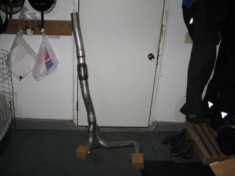 1995 Ford Bronco - A metal exhaust pipe section with a flex joint is shown, supported by wooden blocks.
