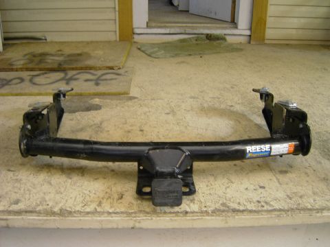 1995 Jeep YJ - A black Reese trailer hitch is displayed on a wooden surface, with a Supermotors.net logo visible at the bottom right.