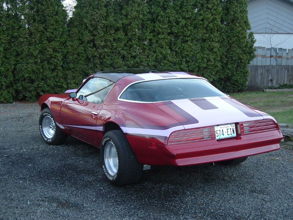 1976 Pontiac Firebird Formula with red paint, white stripes on hood and trunk, and custom side graphics. License plate reads 574-EIN