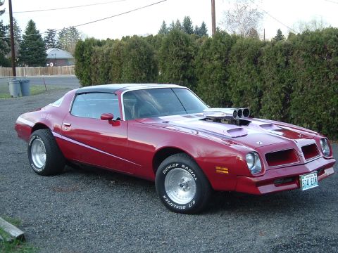 1976 Pontiac Firebird - This 1976 Pontiac Firebird features a large hood scoop and custom wheels, seen from the front three-quarter view.