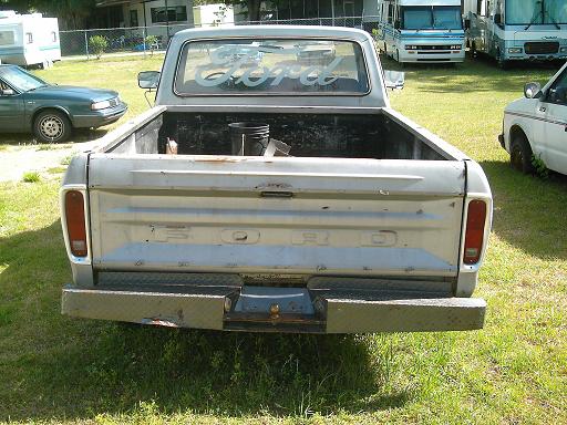 Rear view of a silver Ford pickup truck with diamond plate bumper. Ford lettering on tailgate