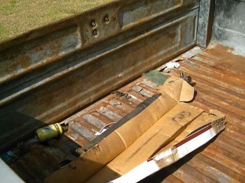 1986 Ford Bronco - Interior of a rusty truck bed containing a can and some wrapped objects.