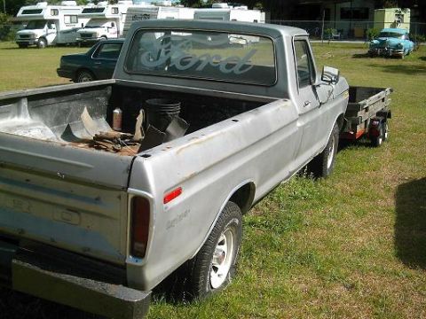 1986 Ford Bronco - A silver Ford pickup truck is parked on a grassy area with several RVs and other vehicles in the background.
