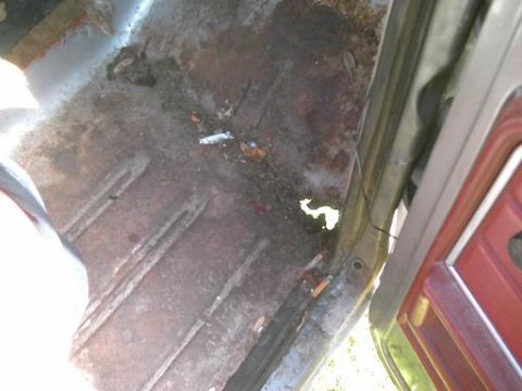 1986 Ford Bronco - The floor of the vehicle's interior shows significant rust and debris, indicating a need for restoration.