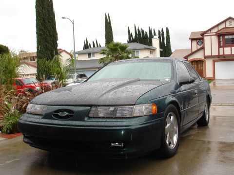 1993 Ford Taurus - This 1996 Ford Taurus has an aftermarket hood and is parked outside in the rain.