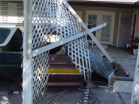 1979 Ford Bronco - A damaged white lattice structure partially obscures a maroon and yellow striped pickup truck bed in a yard.