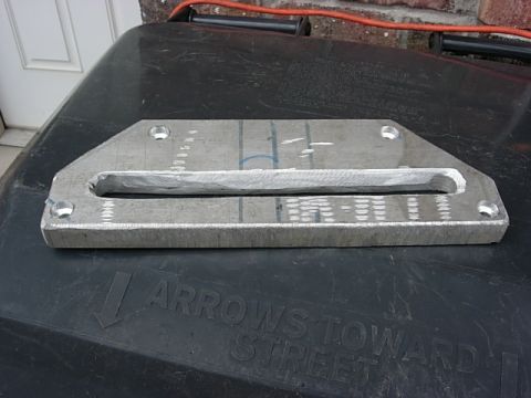 1987 Ford Bronco - A metal winch part is shown, resting on a textured black surface with visible text and markings.
