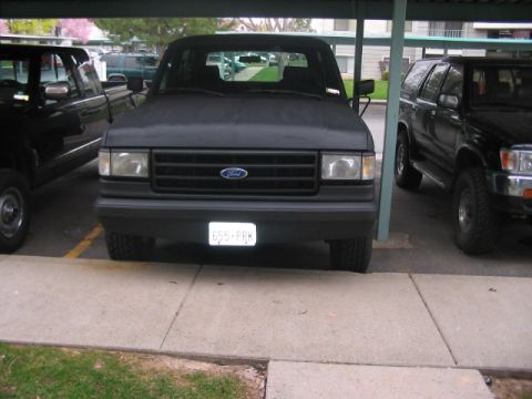 1991 Ford Bronco - A black 1991 Ford Bronco is parked under a carport, showing its front grille and headlights.