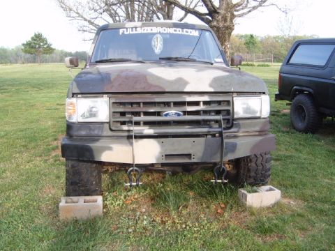 1988 Ford Bronco - Camouflaged 1988 Ford Bronco parked outside, with another vehicle visible to the right.