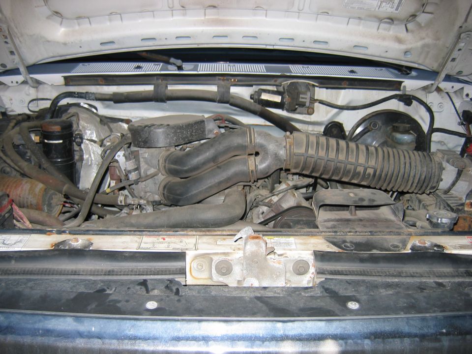 Engine bay of a truck showing intake tubing, radiator and core support, hood open