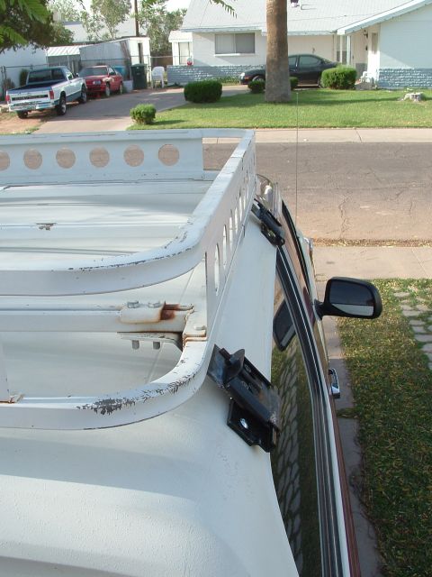 1990 Ford Bronco - Elevated view along the passenger side of a white fiberglass SUV hardtop showing a white-painted tubular roof rack with round lightening ho…