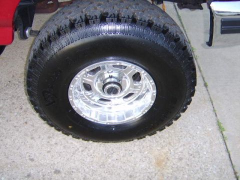 1989 Ford Bronco - Close-up of a vehicle's wheel and tire, with a portion of the red fender visible.