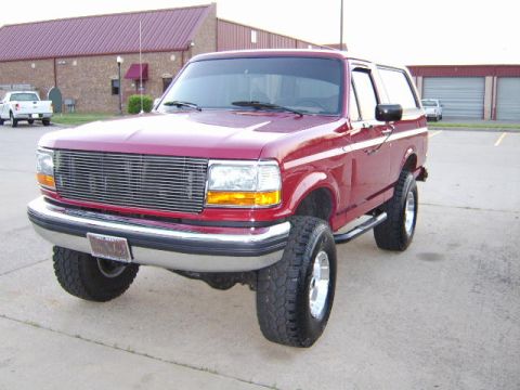 1989 Ford Bronco - This red Ford Bronco features a custom chrome grille and lifted suspension.
