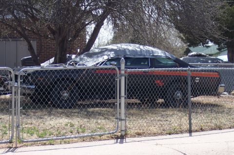 1972 Ford Ranchero - Two vehicles are parked in a yard, partially obscured by tarps and a chain-link fence.