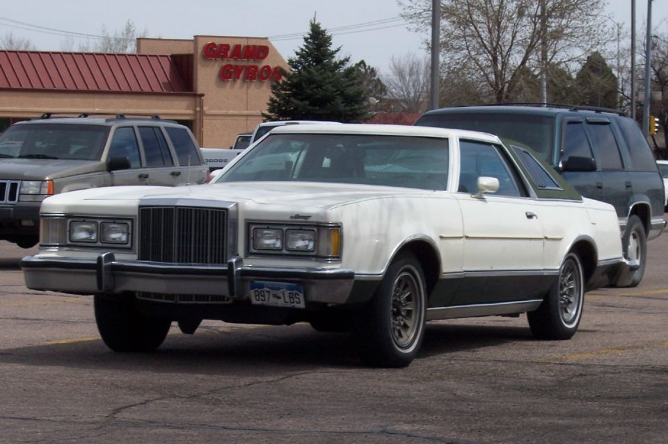 White two-door coupe with a dark green roof and lower body, parked in a lot