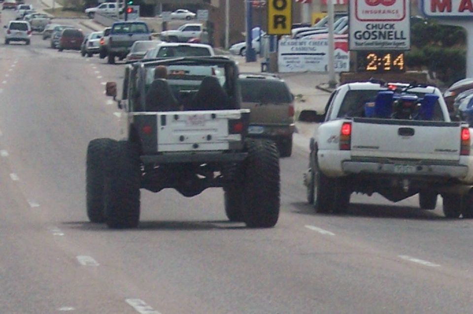 Rear view of lifted Jeep Wrangler with large tires on a highway