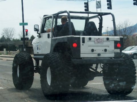 1972 Ford Ranchero - Rear view of a heavily modified Jeep Wrangler with oversized tires and a roll cage.