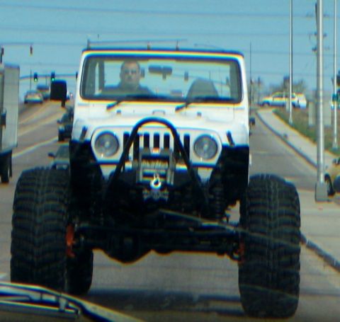 1972 Ford Ranchero - A heavily modified Jeep Wrangler with oversized tires is seen driving down a road.
