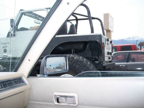 1972 Ford Ranchero - View from inside a vehicle shows the side mirror reflecting other vehicles and a Jeep Wrangler parked nearby.