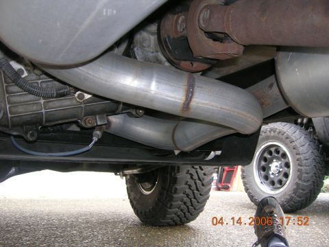 1996 Ford Bronco - Close-up view of the exhaust system and drivetrain components from underneath a vehicle.