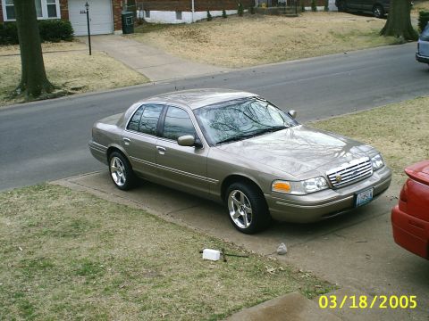 2000 Ford Crown Victoria - Tan 2000 Ford Crown Victoria sedan parked on a concrete driveway next to a lawn.