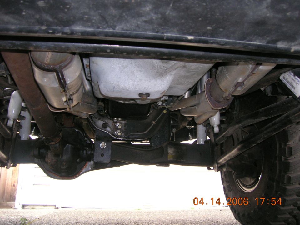 Undercarriage of a 4x4 showing solid front axle, leaf springs and dual catalytic converters