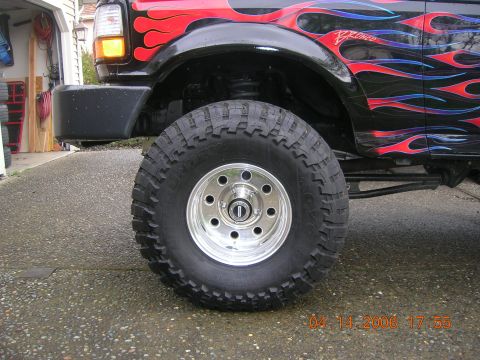 1996 Ford Bronco - A black Ford Bronco with custom flame decals and lifted suspension is shown from the side.