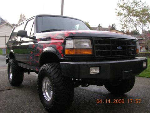 1996 Ford Bronco - Modified 1996 Ford Bronco with custom flame graphics and off-road tires.