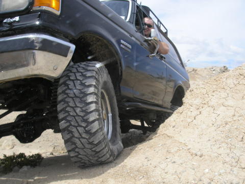 1988 Ford Bronco - A black 1987 Ford Bronco navigates a challenging off-road terrain with a driver visible.
