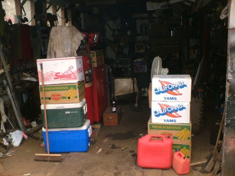 1989 Ford Bronco - A cluttered garage scene with stacked boxes, coolers, and a gas can.