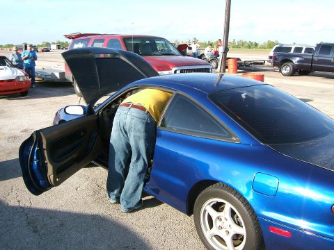 1996 Ford Probe - A person inspects the interior of a blue coupe at an outdoor event with other vehicles present.
