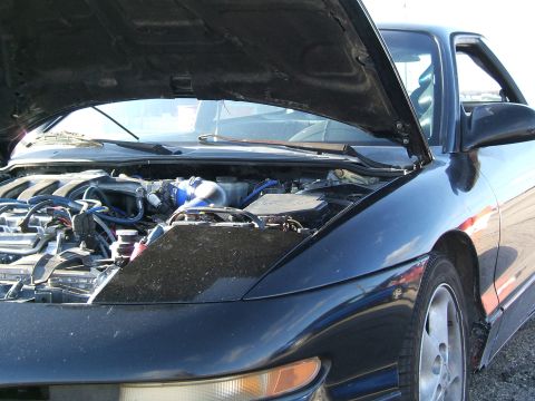 1996 Ford Probe - The engine bay of a black 1996 Ford Probe is visible with the hood raised.