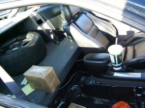 1996 Ford Probe - The interior of a car shows leather seats, a spare tire, and a box on the floor, with a drink in the center console.