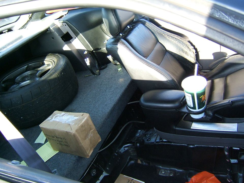 Interior view of a car with leather seats, spare tire, and a box on the floor