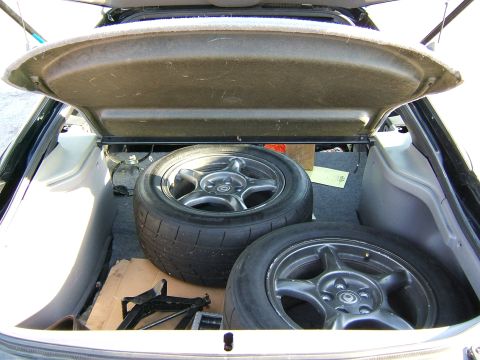 1996 Ford Probe - Spare wheels and tires stored in the trunk of a car, along with a jack.