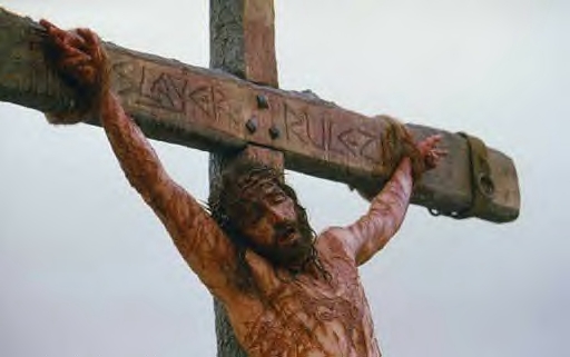 Crucifixion image with graffiti lettering carved across the wooden crossbeam