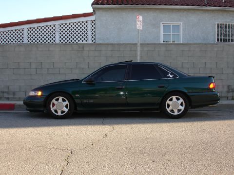 1993 Ford Taurus - Side profile of a dark green 1993 Ford Taurus sedan parked on a street.
